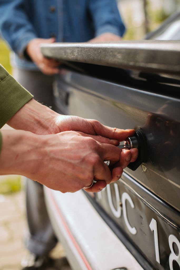 Hand of a Person Unlocking a Black Car's Trunk